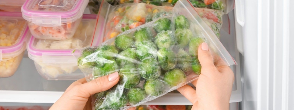 woman-putting-plastic-bag-with-frozen-vegetables-into-refrigerator-min